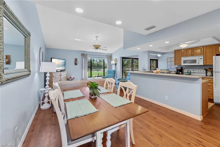 Dining area with ceiling fan, light wood-style floors, a tray ceiling, and recessed lighting