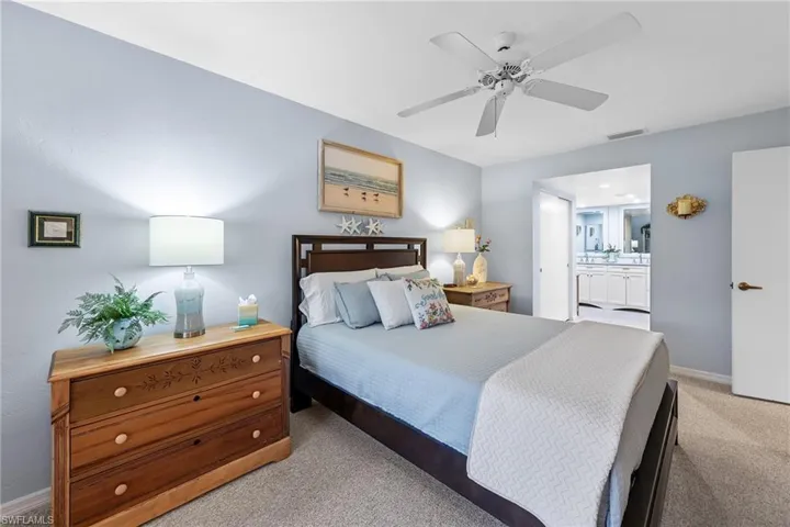 Bedroom with light colored carpet, a ceiling fan, and ensuite bath