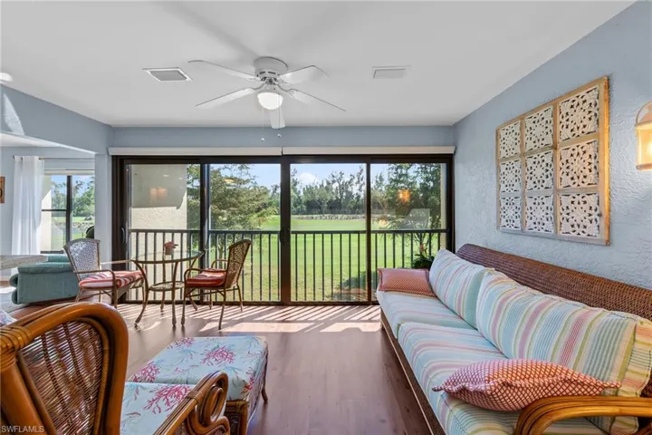 Living area with a ceiling fan, a textured wall, wood finished floors, and plenty of natural light