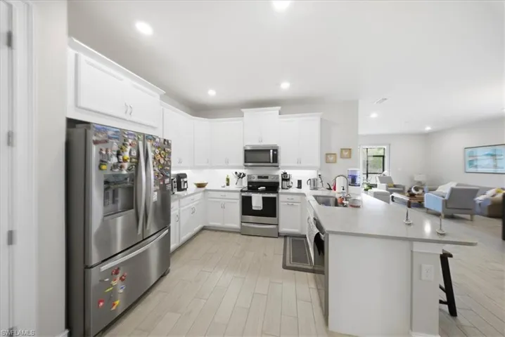 Kitchen featuring stainless steel appliances, a peninsula, white cabinetry, open floor plan, and a breakfast bar