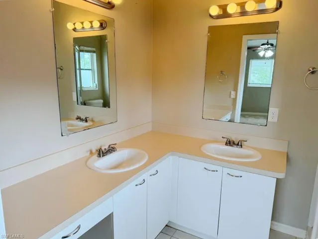 Bathroom featuring plenty of natural light, ceiling fan, double vanity, and toilet