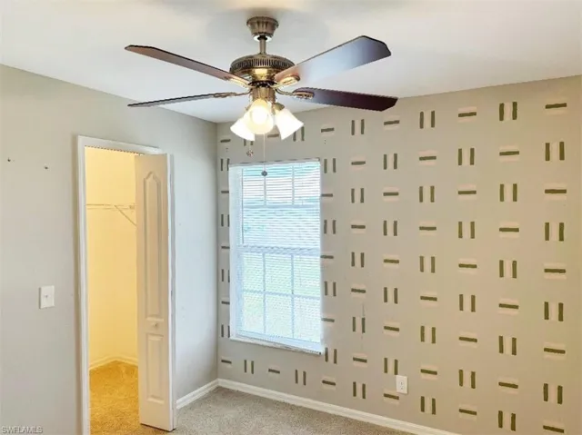 Unfurnished bedroom with ceiling fan, a spacious closet, a closet, carpet, and multiple windows