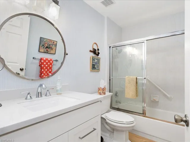 Full bathroom with vanity, toilet, and combined bath / shower with glass door