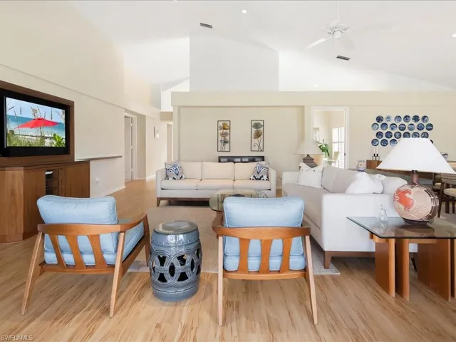 Living room featuring ceiling fan, high vaulted ceiling, and light hardwood / wood-style flooring