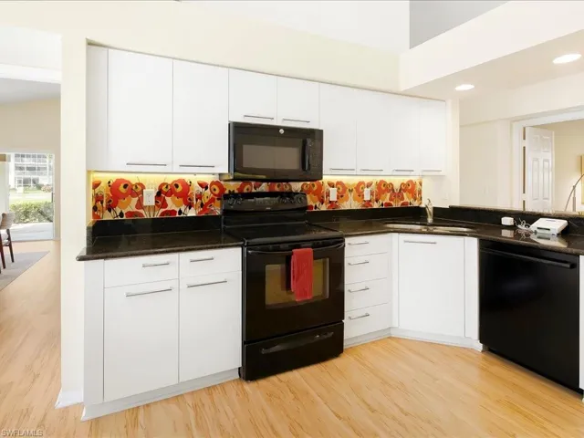 Kitchen featuring sink, white cabinets, light wood-type flooring, and black appliances