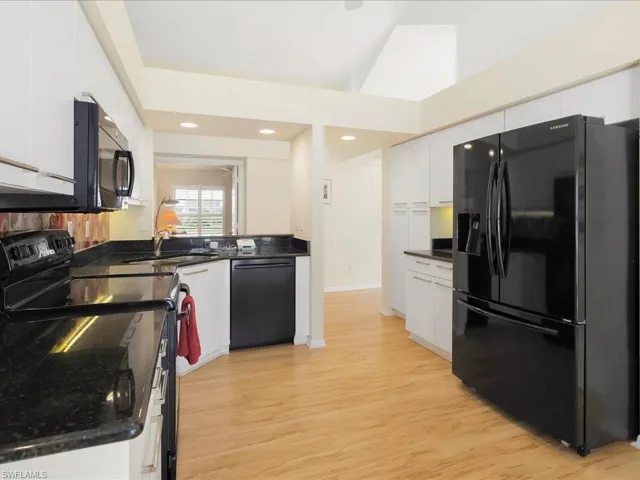 Kitchen with white cabinetry, sink, light hardwood / wood-style flooring, and black appliances