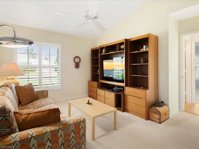 Living room featuring lofted ceiling, light carpet, and ceiling fan