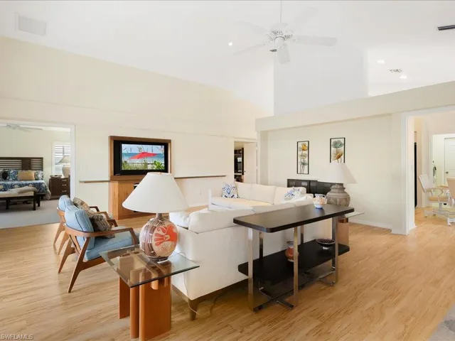 Living room with ceiling fan, light hardwood / wood-style floors, and a high ceiling