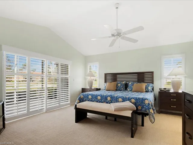 Carpeted bedroom featuring ceiling fan, lofted ceiling, and access to outside