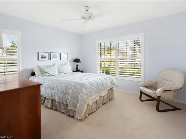 Carpeted bedroom with multiple windows and ceiling fan