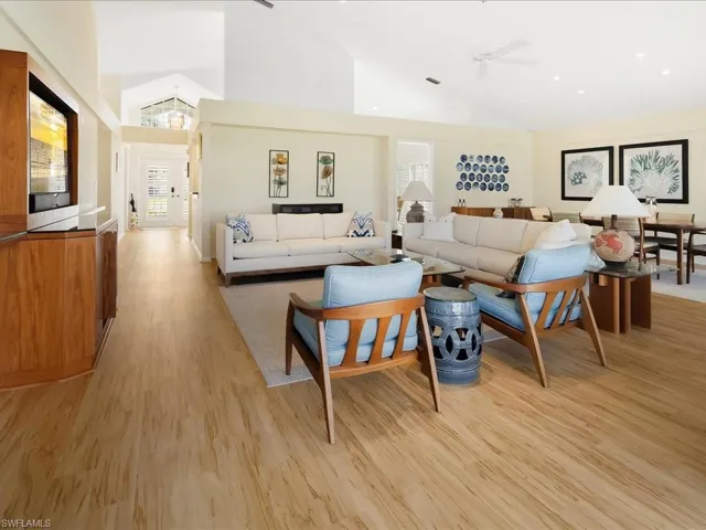 Living room with ceiling fan, high vaulted ceiling, and light wood-type flooring
