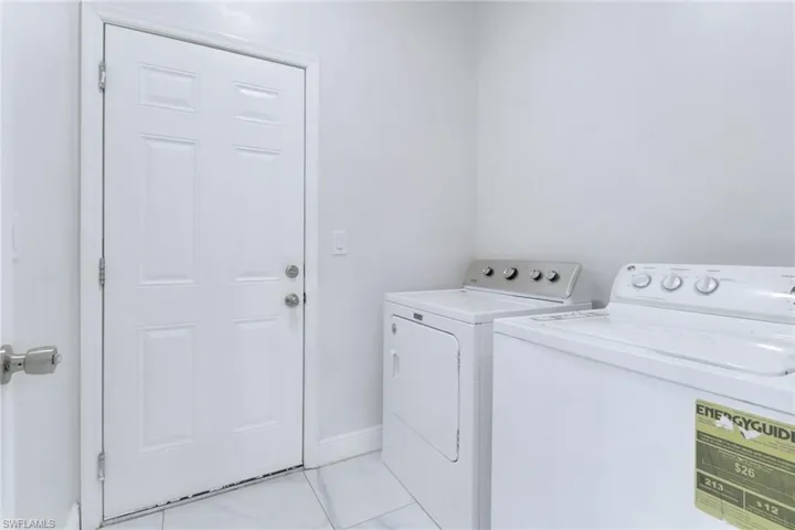 Washroom with separate washer and dryer and light tile patterned floors
