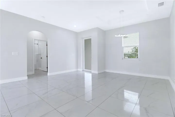 Unfurnished room featuring arched walkways and baseboards