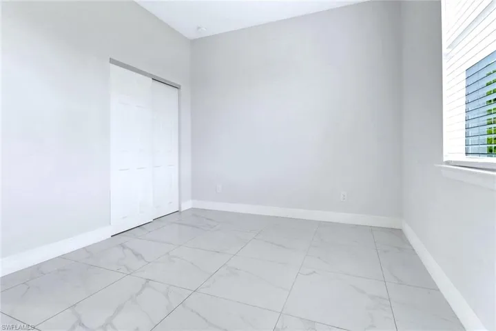 Unfurnished bedroom featuring light marble finish floors and a closet