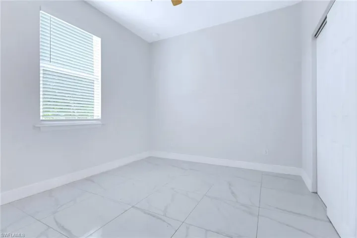 Unfurnished room with light marble finish floors and a ceiling fan