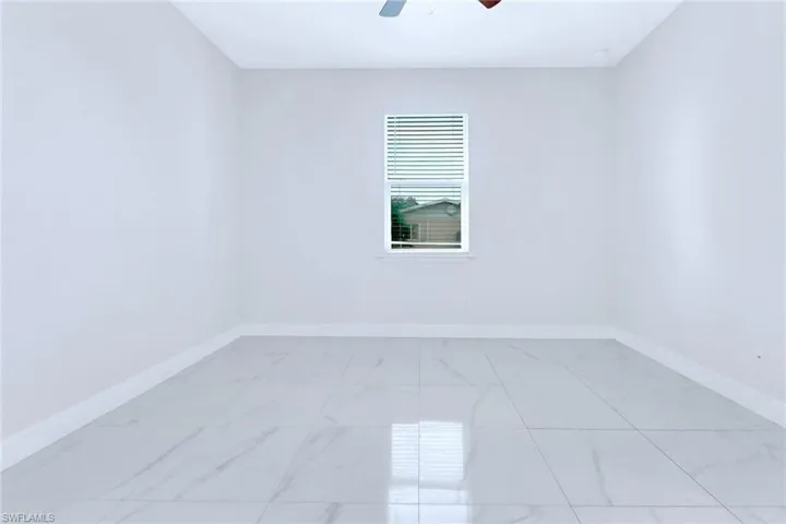 Unfurnished room with a ceiling fan and light marble finish flooring