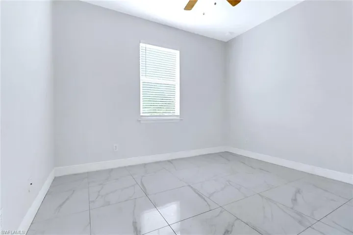Unfurnished room featuring light marble finish flooring and a ceiling fan