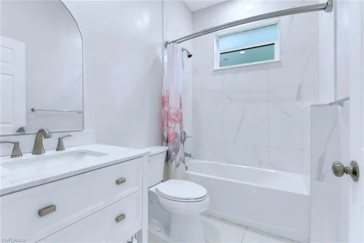 Full bath with shower / bath combination with curtain, vanity, and tile patterned flooring