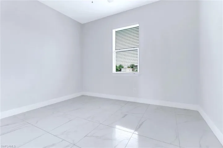 Spare room featuring light marble finish flooring and baseboards
