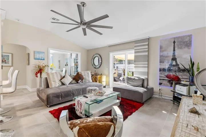 Living room with lofted ceiling, ceiling fan, arched walkways, and light ceramic tiled floors