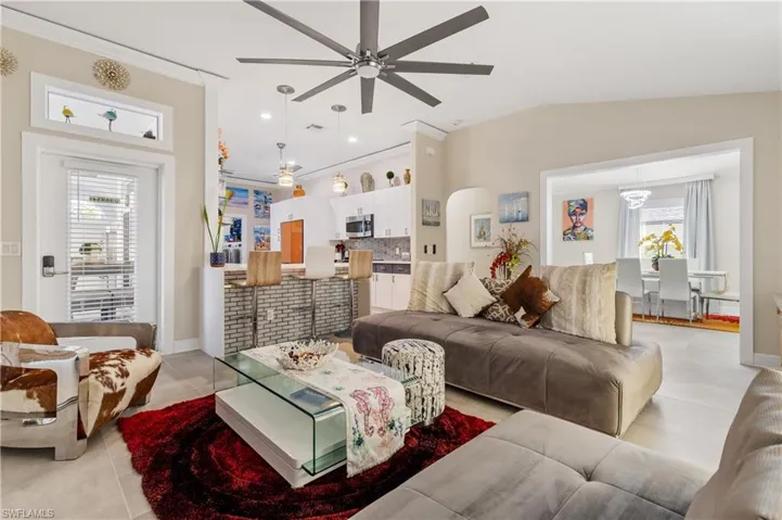 Living area with ceramic tile floors, ceiling fan, recessed lighting, lofted ceiling, and ornamental molding