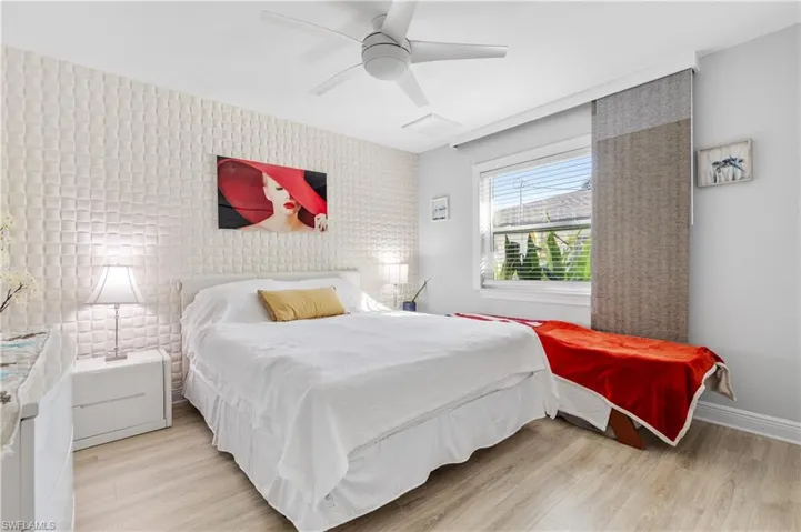 Second bedroom featuring waterproof laminate flooring, a ceiling fan, and an accent 3D wall