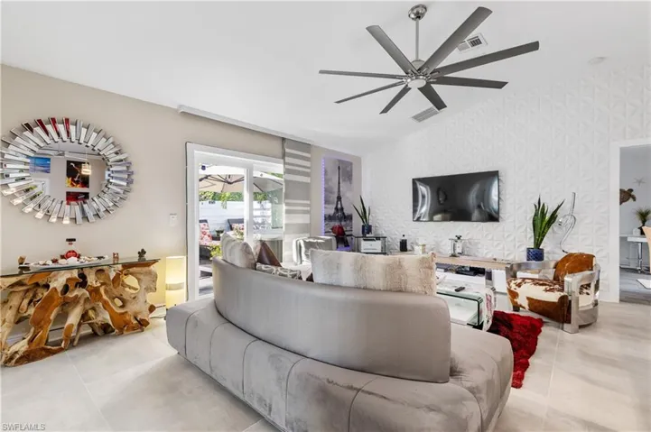 Living room with vaulted ceiling, 3D wall accent walls, an accent wall, ceiling fan,