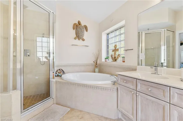 Bathroom featuring vanity, a shower stall, light tile patterned flooring, and a bath