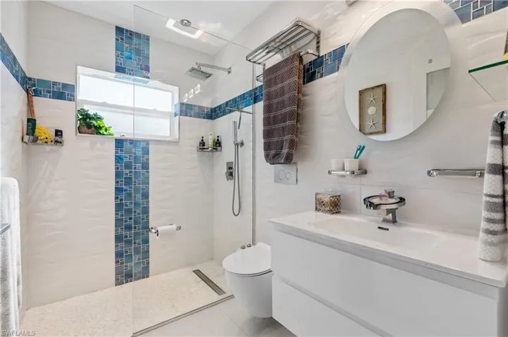 Second bathroom with a walk-in shower, vanity, tile walls, and tile patterned floors