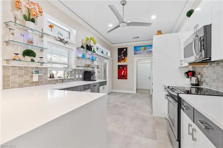 Kitchen featuring backsplash, quartz counters, stainless steel appliances, open shelves,