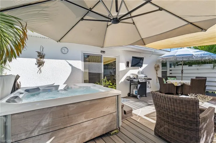 Composite terrace featuring a hot tub, a grill and outdoor dining area