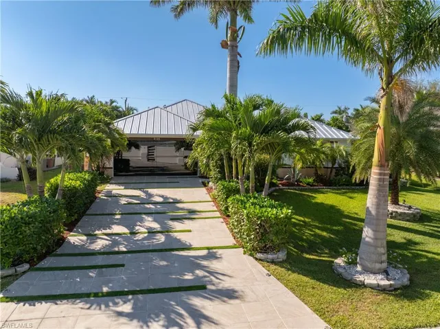 Frontal view of home with a front yard tiled driveway and glass garage door