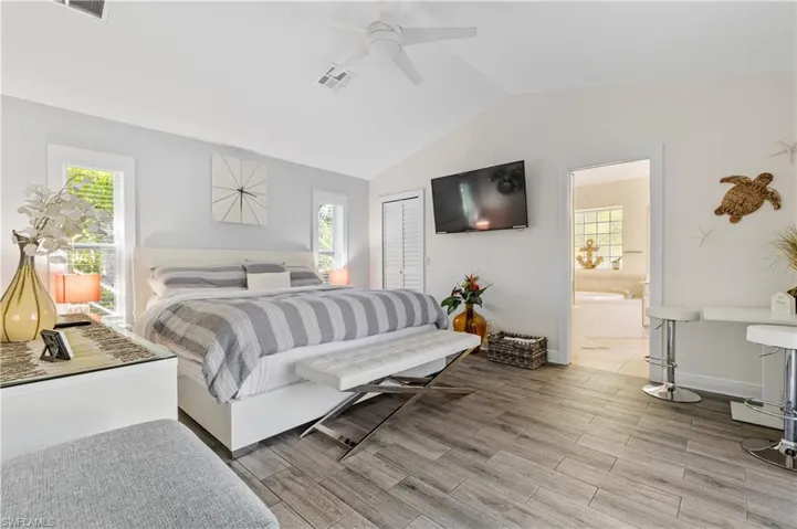 Primary Bedroom with plank tile floors, vaulted ceiling, and walk-in closet