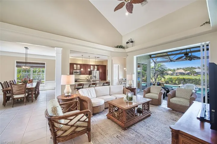 Living room featuring ceiling fan, high vaulted ceiling, light tile patterned floors, and ornate columns