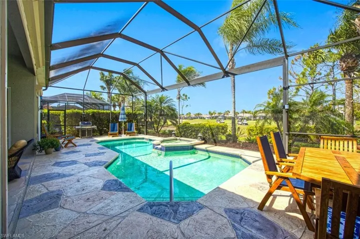 View of pool with glass enclosure, a patio area, and a pool with connected hot tub