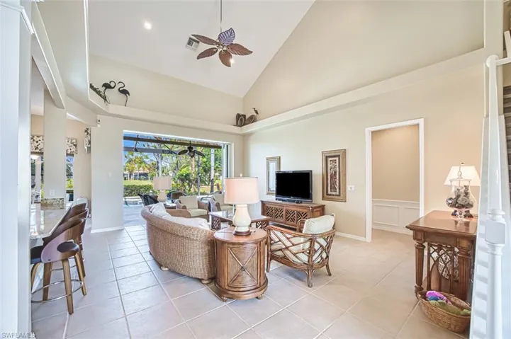 Living area featuring a sunroom, light tile patterned floors, high vaulted ceiling, and a ceiling fan