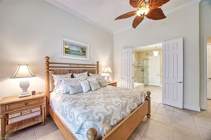 Bedroom with light tile patterned floors, ensuite bath, baseboards, and crown molding
