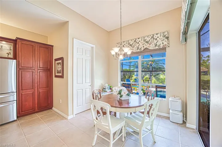 Dining space with baseboards, a notable chandelier, and light tile patterned flooring