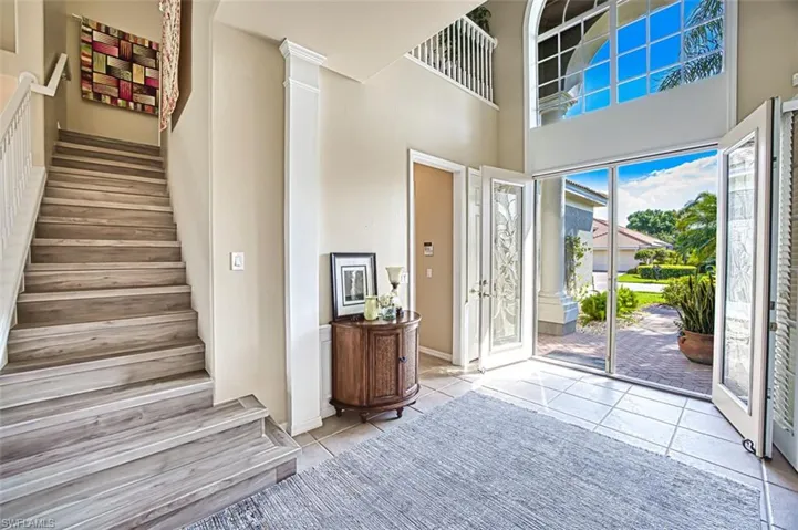 Tiled foyer entrance featuring stairs, a high ceiling, decorative columns, and baseboards