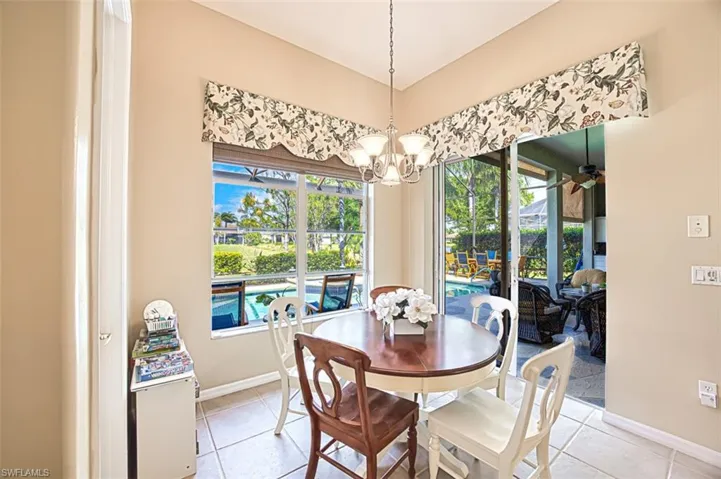 Dining space featuring an inviting chandelier, light tile patterned floors, baseboards, and a sunroom