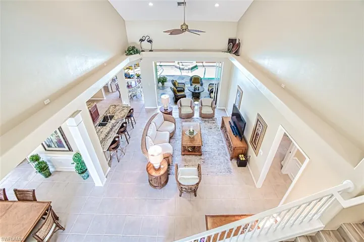 Living room with a ceiling fan, a towering ceiling, tile patterned floors, stairs, and recessed lighting