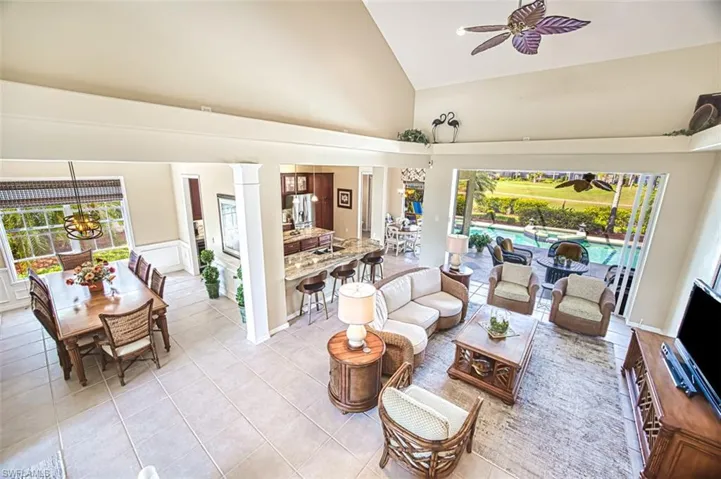 Living room with decorative columns, high vaulted ceiling, a ceiling fan, and light tile patterned flooring