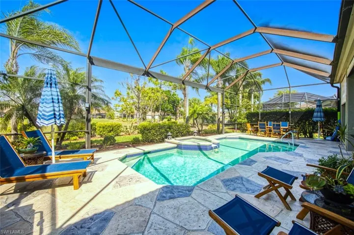 View of swimming pool featuring a patio, glass enclosure, and a pool with connected hot tub