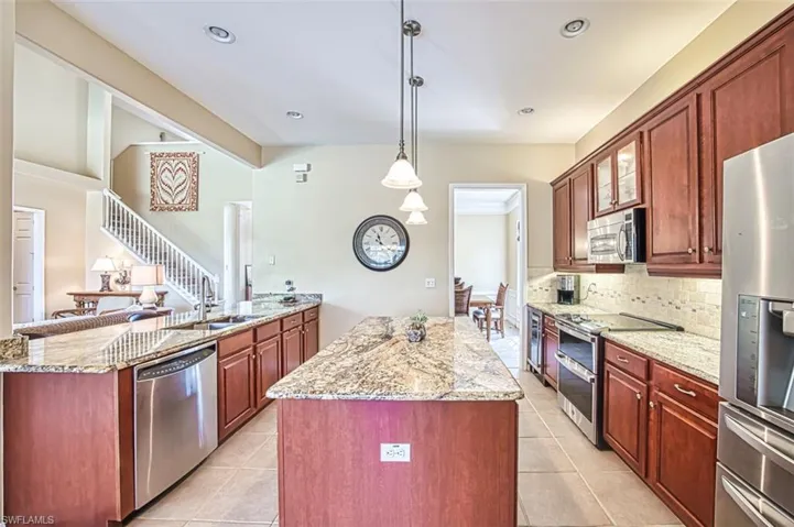 Kitchen with a sink, a center island, appliances with stainless steel finishes, light stone countertops, and tasteful backsplash