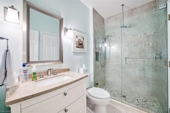 Bathroom featuring toilet, a shower stall, and vanity