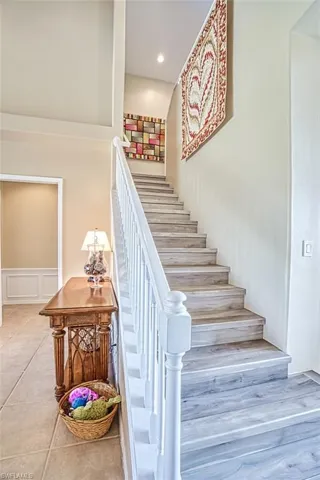 Staircase featuring a wainscoted wall, recessed lighting, a decorative wall, and tile patterned floors