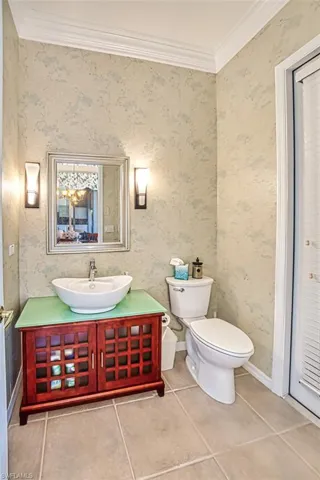 Bathroom featuring ornamental molding, tile patterned flooring, toilet, and wallpapered walls