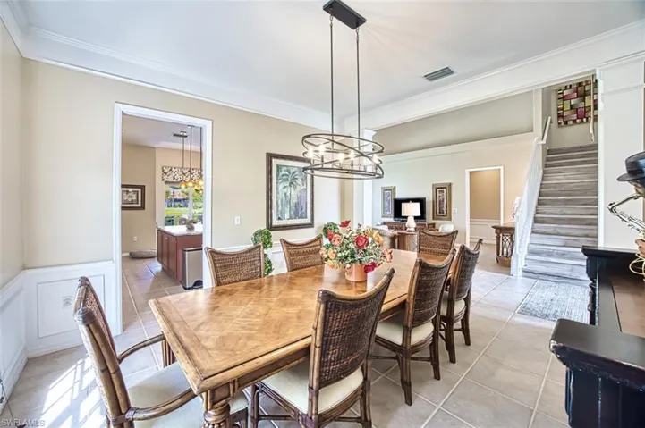 Dining space featuring ornamental molding, light tile patterned floors, visible vents, and stairs