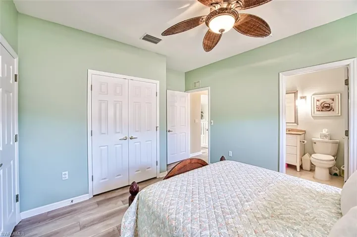Bedroom with light wood finished floors, baseboards, visible vents, a ceiling fan, and a closet