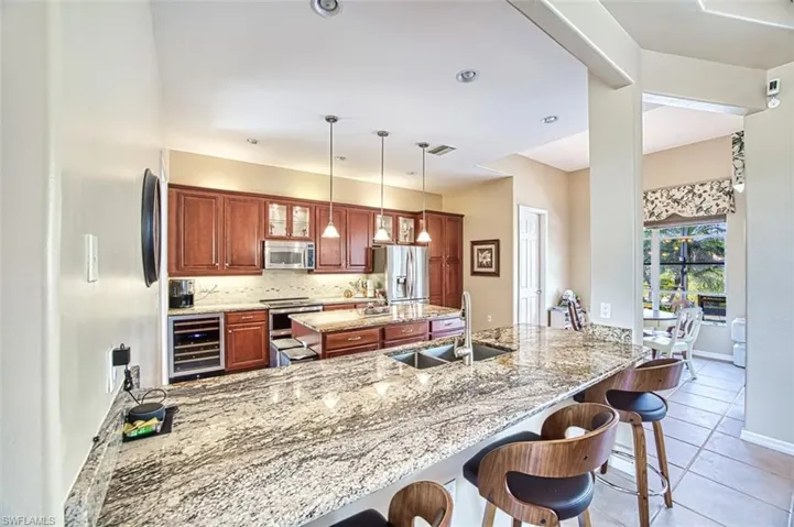 Kitchen featuring stainless steel appliances, tasteful backsplash, a sink, beverage cooler, and a peninsula